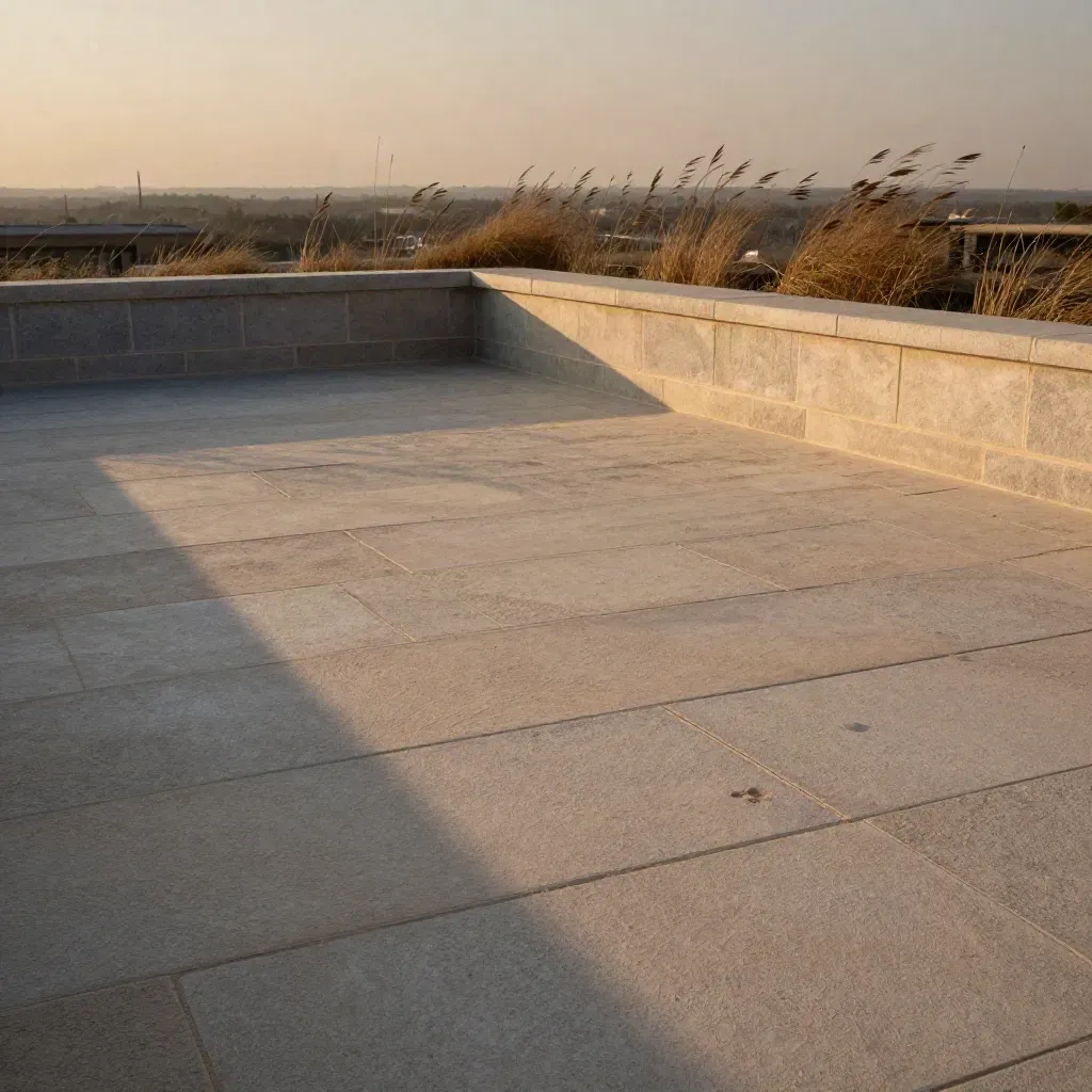 Sunlit sandstone rooftop terrace with dry grasses and a hazy skyline at dusk.